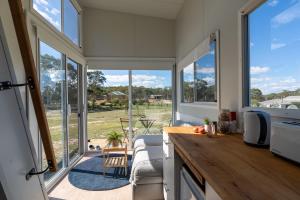 a kitchen with large windows and a view of a yard at Saddle Camp Tiny House by Tiny Away in Braidwood