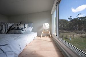 a bedroom with a bed and a large window at Saddle Camp Tiny House by Tiny Away in Braidwood
