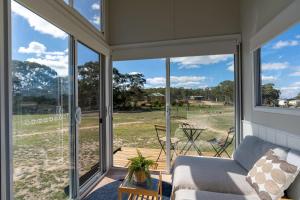 a screened porch with a couch and a view of a field at Saddle Camp Tiny House by Tiny Away in Braidwood