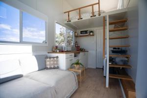 a bedroom with a bunk bed and a kitchen at Saddle Camp Tiny House by Tiny Away in Braidwood