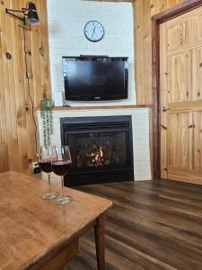 two glasses of wine on a table in front of a fireplace at Refuge Boréal - Bord du lac paisible in Saint-Ambroise