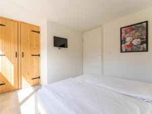 a white bedroom with a bed and a tv at Kuifmees in Hulshorst