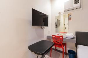 a room with a red chair and a desk with a tv at Hotel Sogo Sta Rosa in Santa Rosa