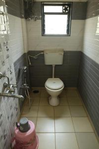 a small bathroom with a toilet and a window at Blue Diamond Dapoli in Murūd