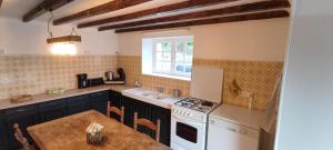 a kitchen with a table and a stove and a sink at Balcon des fées in Le Malzieu-Ville