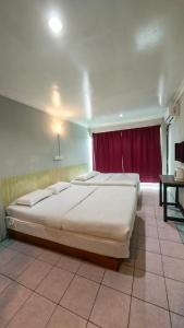 a large bed in a room with a red curtain at Highway Inn in Mukah +15 photos