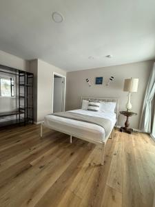 a white bedroom with a bed and wooden floors at Great Lakes Resort - Family Suite - Suite 1 in Lexington