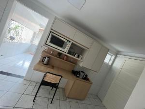 a small kitchen with a microwave and a chair at Casa ampla e confortável in Mossoró