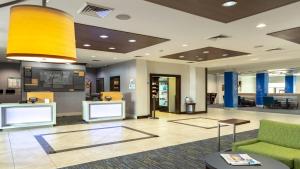 an office lobby with a green couch and a yellow light at Holiday Inn Express & Suites Houston South - Near Pearland by IHG in Houston +43 photos