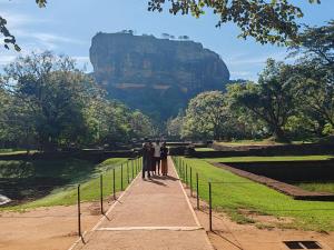 a group of people standing on a walkway with a mountain in the background at Tiny Homestay in Dambulla