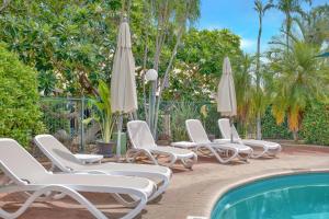 Eine Gruppe von Stühlen und Sonnenschirmen neben einem Pool in der Unterkunft Shell Escape in Broome