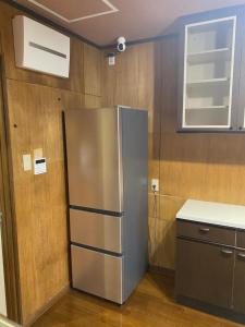 a kitchen with a stainless steel refrigerator in a room at Guest House KURA 776 Mt Fuji View and 1 min to Gekkoji Station in Fujiyoshida