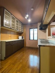 a large kitchen with wooden floors and stainless steel appliances at Guest House KURA 776 Mt Fuji View and 1 min to Gekkoji Station in Fujiyoshida