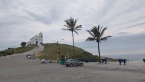 a building on top of a hill with palm trees at Barrinha Beach flats in Saquarema
