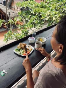 a woman sitting at a table with a plate of food at Casa Moon Trincomalee Beach House in Trincomalee