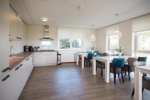 a kitchen with white cabinets and tables and blue chairs at De Oranjerie in Buren