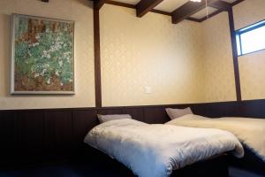 two beds in a room with a painting on the wall at Taisho Roman-style Private Villa with Original Japanese Art 日本画原画の一棟貸し M's Lumos in Marugame