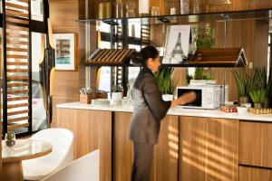 a woman is standing at a counter with a microwave at Hôtel Eiffel Turenne in Paris