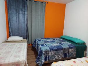 two beds in a room with orange walls at Las Armonías Hostal in Panajachel