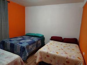 two beds in a room with orange walls at Las Armonías Hostal in Panajachel