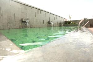 a swimming pool with green water in front of a building at Midtown Hotel Samarinda in Samarinda