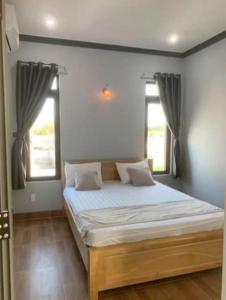 a bedroom with a large bed with two windows at Du Mục in Thôn Mỹ Phước