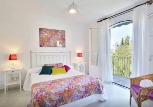 a white bedroom with a bed and a balcony at Casa El Capricho in Marbella