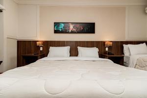a bedroom with a large white bed and a tv on the wall at Flat Serrano com Total Acesso ao Wish Resort in Gramado
