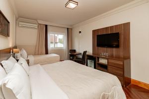 a hotel room with a bed and a flat screen tv at Flat Serrano com Total Acesso ao Wish Resort in Gramado