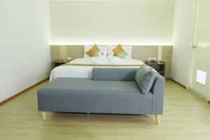 a bedroom with a bed and a blue couch at Le Srivaree Suvarnabhumi Airport Hotel in Samutprakarn