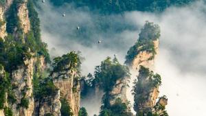 a group of mountains with birds flying in the sky at Zhangjiajie Cloudscape Villa - New Hotel, Free Private Car Rides to South & East Gates of Zhangjiajie National Forest Park,Free Private Car Rides to & from Airport,Chinese-Western Breakfast, Coffee, Tea & Fruit, Free Laundry & Dryer, Ticket Guidan in Zhangjiajie