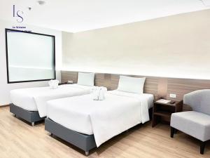 a room with three beds and a chair at Le Srivaree Suvarnabhumi Airport Hotel in Samutprakarn +31 photos