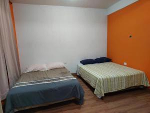 two beds in a room with orange and white walls at Las Armonías Hostal in Panajachel