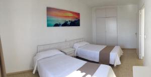 サン・アントニオ・ベイにあるApartamentos Albaのベッド2台が備わる客室で、壁には絵画が飾られています。