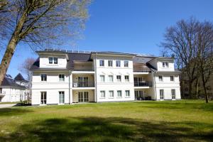 un gran edificio blanco con un gran campo de césped en Haus Pamir - Ferienwohnungen, en Ostseebad Nienhagen