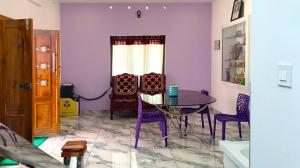 a dining room with purple walls and a table and chairs at Leland Homestay in Mararikulam +42 photos