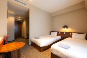 a hotel room with two beds and a table at Koraku Garden Hotel Tokyo in Tokyo