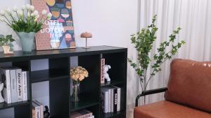 a black book shelf with books and flowers and a chair at 호텔 도토리 in Gunsan-si +9 photos