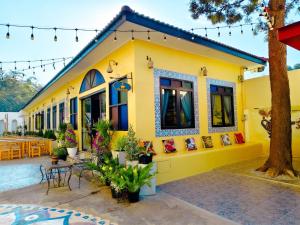 a yellow building with a table and chairs at La Reina Maroc Hotel ปากช่อง เขาใหญ่ in Pak Chong