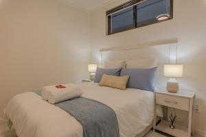 a bedroom with a bed with blue pillows and a window at The Stay Edit Windhoek in Windhoek