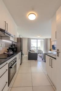 a kitchen with white cabinets and a living room at The Stay Edit Windhoek in Windhoek