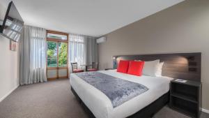 a hotel room with a large bed with red pillows at Carnmore Hotel Lower Hutt in Lower Hutt