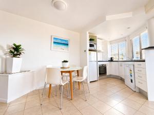 a kitchen and dining room with a table and chairs at Stylish 1 Bedroom with Private Rooftop Spa at the Aegean in Mooloolaba