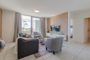a living room with a couch and chairs and a tv at The Stay Edit Windhoek in Windhoek