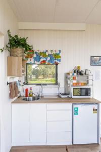 a kitchen with white cabinets and a sink and a window at Tiny Balloon House by Tiny Away in Canowindra