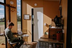 a man sitting in a chair in a room with a laptop at Tiny Boorowa by Tiny Away in Boorowa