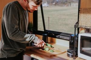 a man cutting up vegetables on a cutting board at Tiny Boorowa by Tiny Away in Boorowa