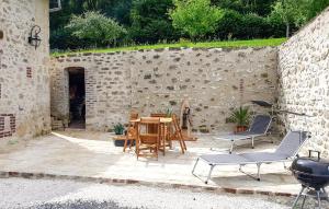 a patio with a table and chairs and a stone wall at Grange En Campagne in Vauxaillon