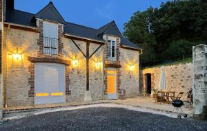 a stone house with a patio and a table at Grange En Campagne in Vauxaillon +19 photos
