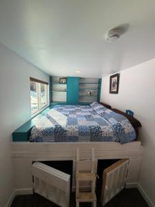 a bedroom with a bed with a blue and white quilt at Cozy Container in Soldotna